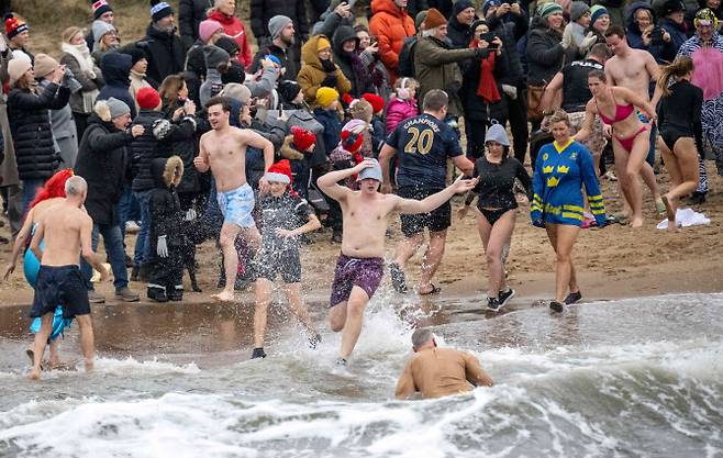 2026년 1월 1일(현지시간) 스웨덴 남부 한 해수욕장에서 전통적인 새해 바다 수영 행사에 참가한 겨울 수영객들이 바다로 뛰어들고 있다. (사진=AFP)