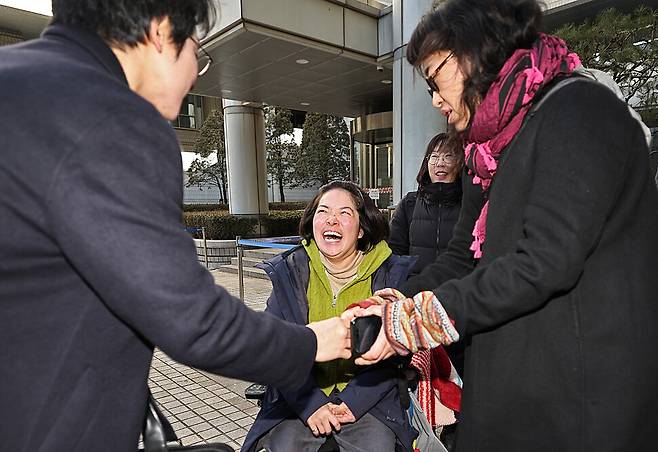 장애인 활동가 문애린(가운데)씨와 비장애 활동가 한명희(오른쪽)씨가 2026년 1월29일 서울 서초구 서울중앙지방법원에서 열린 선고공판을 마친 뒤 변호인단과 인사를 나누고 있다.
