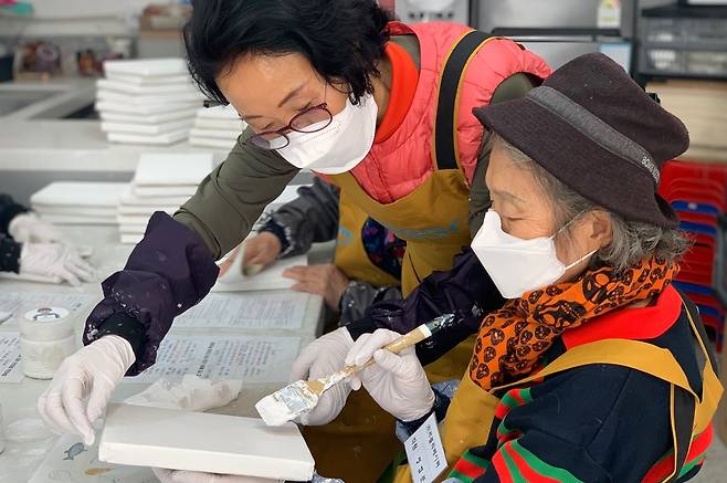 Artists hired by the nonprofit organization LoveRe: Paper paint on canvases made from discarded paper that has been collected. [LOVERE: PAPER]
