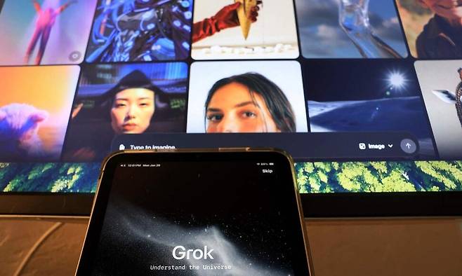 일론 머스크가 출시한 대화형 인공지능 ‘그록’ 애플리케이션을 켠 태블릿 뒤로, 컴퓨터 화면에 인공지능 이미지·영상 생성 사이트인 ‘그록 이매진’의 모습이 보인다. AFP 연합뉴스
