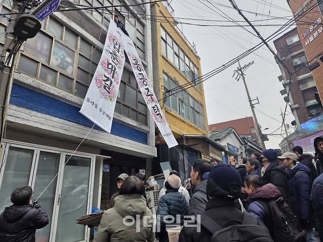4일 오전 서울 용산구 동자동 쪽방촌의 한 건물 외벽에 ‘공공주택사업 촉구’를 기리는 입춘첩을 매달고 있는 연대 시민들의 모습이다. (사진=염정인 기자)
