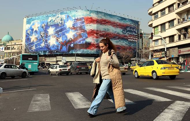 26일(현지시간) 이란 테헤란 혁명광장에서 여성들이 건물 외벽에 설치된 반미(反美) 광고판 앞을 지나고 있다. AFP =연합뉴스