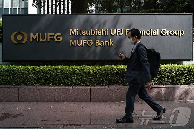 일본 도쿄에 있는 미쓰비시 UFJ 파이낸셜 그룹과 MUFG 은행 본사 앞 간판을 한 보행자가 지나가고 있다. 2021.9.22. ⓒ AFP=뉴스1 ⓒ News1 이정환 기자