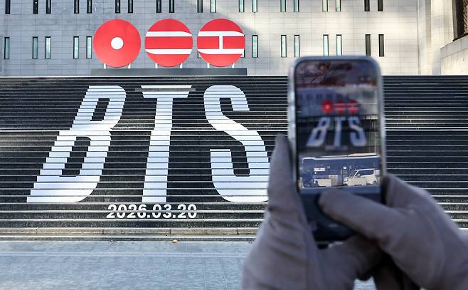 서울 종로구 세종문화회관 계단에 설치된 방탄소년단(BTS)의 정규 5집 컴백을 알리는 홍보물을 배경으로 관광객들이 기념촬영을 하고 있다./뉴스1