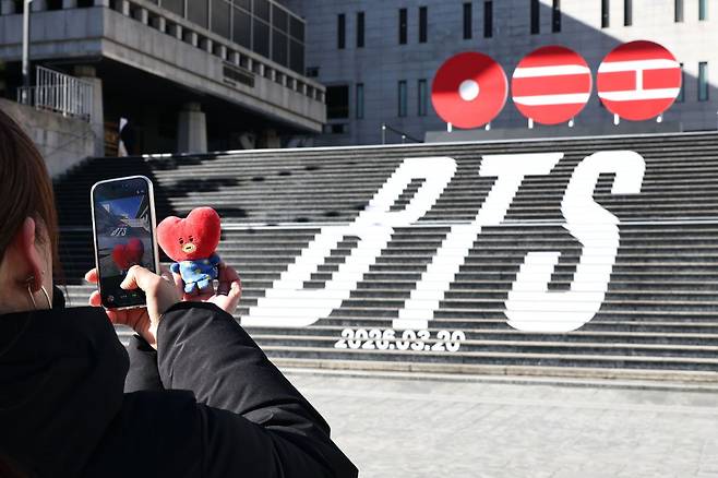 일본인 관광객이 지난달 22일 서울 종로구 세종문화회관 계단에서 방탄소년단(BTS)의 컴백을 알리는 홍보물을 배경으로 기념사진을 촬영하고 있다. 연합