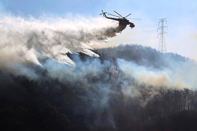 8일 경북 경주시 문무대왕면 산불이 강풍을 타고 주변으로 확산하는 가운데 산불 진화에 투입된 헬기가 송전탑 주변을 날아가며 산불을 진화하고 있다. 경주=뉴스1