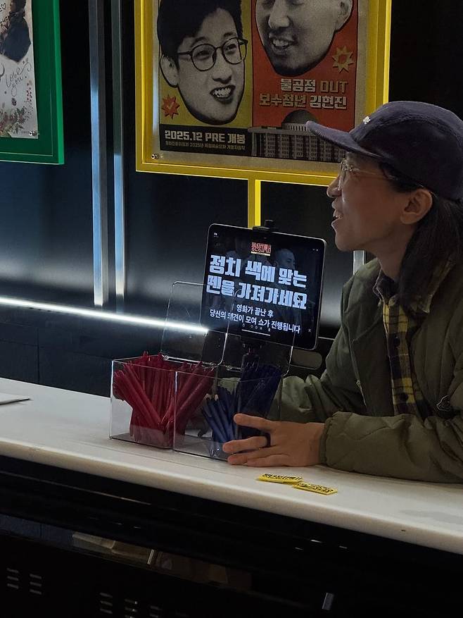이일하 감독이 지난달 24일 서울 마포구 인디스페이스에서 열린 <청년정치백서-쇼미더저스티스> 상영 및 청정백쇼에 앞서 관객들에게 설문지를 작성할 펜을 나눠주고 있다. ‘정치색에 맞는 펜을 가져가라’며 빨간색과 파란색 펜이 준비되어 있다. 이날 청정백쇼에는 이 감독과 김창인, 장혜영 전 의원이 참여하고 김정각 스탠드업 코미디언이 사회를 봤다. 익스포스 필름 인스타그램(@exfilm_official) 갈무리