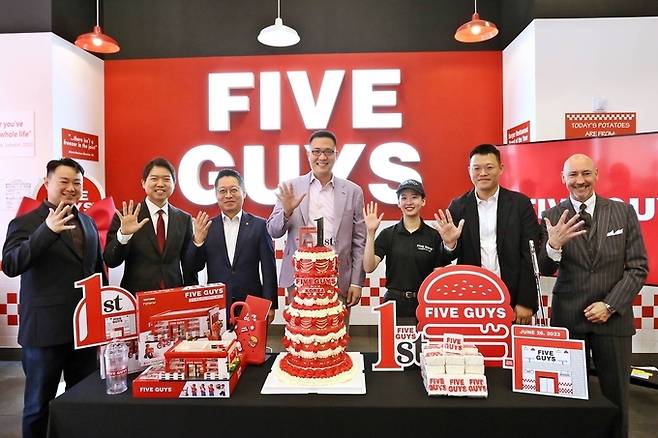 Hanwha Galleria Vice President Kim Dong-seon (center), participates in a cake-cutting ceremony with officials at Five Guys’ first outlet in Korea, in Gangnam, southern Seoul, celebrating the branch's first anniversary in June 2024. (FG Korea).