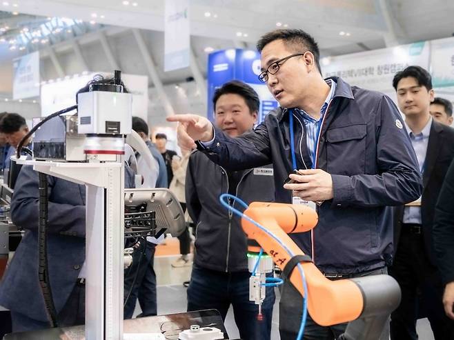 Kim Dong-seon, vice president of Hanwha Hotel & Resorts and Hanwha Robotics, examines a cooperative robot at a tech trade show in Seoul. (Hanwha Robotics)