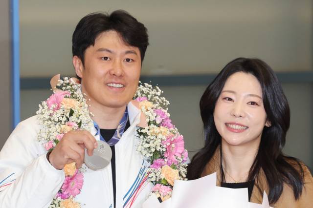 ▲ 2026 밀라노-코르티나담페초 동계 올림픽 스노보드 남자 평행대회전에서 은메달을 차지한 한국 스노보드 국가대표팀 김상겸(왼쪽)이 10일 인천국제공항을 통해 귀국한 뒤 아내와 기념 촬영하고 있다. 연합뉴스