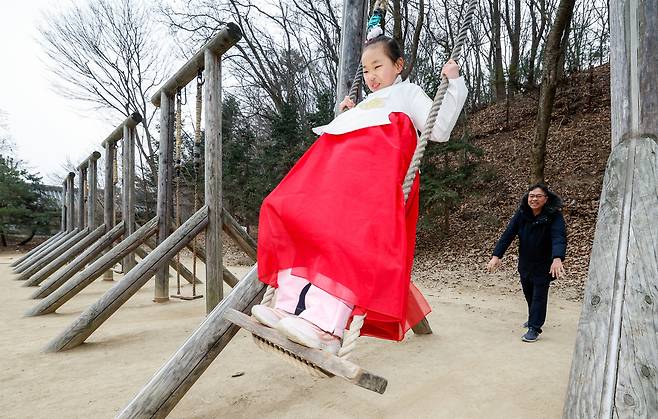 설 연휴를 앞둔 10일 경기 용인시 한국민속촌에서 한복을 입은 어린이가 아빠가 밀어주는 그네를 타고 있다.&nbsp;