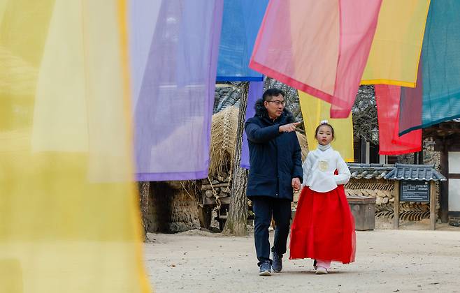 설 연휴를 앞둔 10일 경기 용인시 한국민속촌에서 한복을 입은 어린이가 아빠와 함께 손을 잡고 걷고 있다.&nbsp;