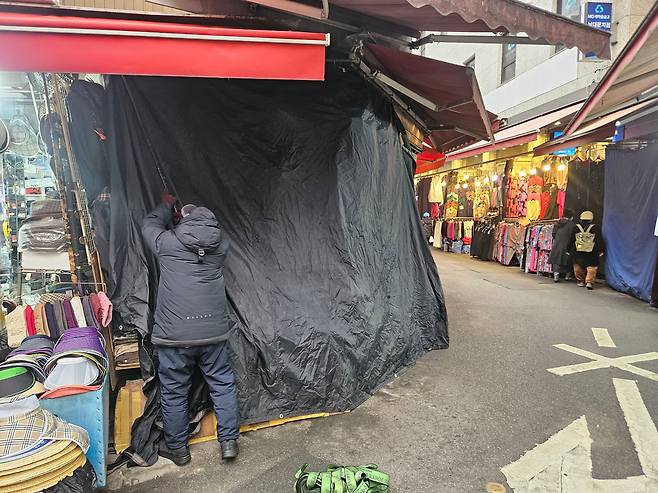 지난 4일 오후 5시쯤 서울 중구 남대문시장에서 남성복 매장을 운영하는 상인이 천막을 두르며 가게 문을 닫고 있다. 70대인 이 남성 상인은 “예전에는 24시간 영업했는데, 요즘은 장사가 안 돼 오후 4시만 돼도 가게 문을 일찍 닫는다”고 말했다. /지혜진 기자