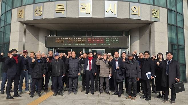 박태경 전 화성시 민생경제산업국장(사진 가운데 빨간색 목도리)과 관계자들이 11일 화성특례시의회 앞에서 기념촬영을 하고 있다. 사진=박태경 출마예정자 제공.