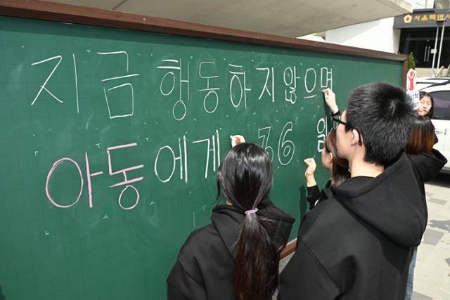 2024년 4월 세이브더칠드런의 아동·청소년 모임 '세이브더칠드런 지구기후팬클럽 어셈블'이 지구의 날을 맞아 서울 중구 서울도시건축전시관 앞에서 '지금 행동하지 않으면 아동에게는 365일이 재난입니다'라고 쓰는 퍼포먼스를 하고 있다. 정다빈 기자