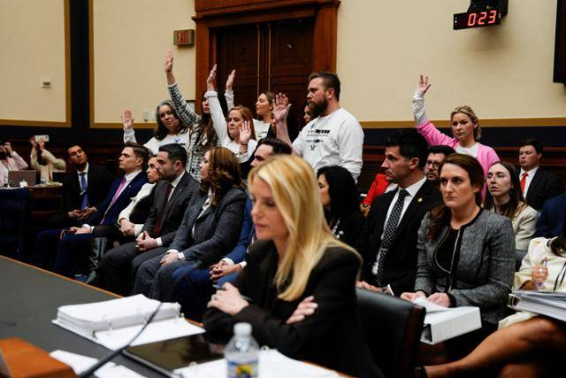 팸 본디 미국 법무장관이 11일 워싱턴 국회의사당에서 열린 하원 법사위원회 청문회에 출석해 있는 가운데, 미국 억만장자 성범죄자 제프리 엡스타인 사건의 피해자들이 흰 옷을 입은 채 댄 골드먼(뉴욕·민주) 하원의원의 "피해자들 중 본디 장관을 만난 적이 없는 사람이 누구냐"는 질문을 받고 손을 들어 보이고 있다. 워싱턴=로이터 연합뉴스