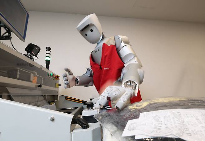 지난달 29일 서울 광운대 누리관 로봇제어실험실에서 인간형 로봇 '이그리스-C'가 자동 택배 포장 기계인 '오토 배거'를 버튼으로 조작하면서, 폴리백(작은 물건용 비닐 포장재) 포장법을 학습하고 있다. 하루 20~30번씩 원격 조종을 통해 다양한 색상·형태의 물건을 포장하며 '연습' 중이다. /장경식 기자