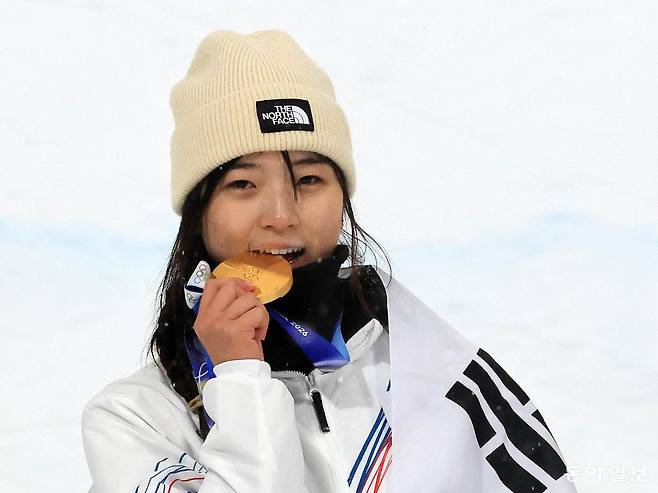 12일(현지 시각) 이탈리아 리비뇨 스노우파크에서 열린 겨울올림픽 스키 스노보드 여자 하프파이프 결선에서 한국 최가온이 90.25점으로 금메달을 목에 건 뒤 메달을 깨물고 있다. 리비뇨=전영한 기자 scoopjyh@donga.com