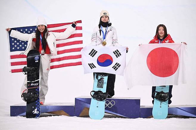 From left: Silver medalist Chloe Kim, gold medalist Choi Gaon and bronze medalist Mitsuki Ono celebrate on the podium after the snowboard women's halfpipe final during the 2026 Winter Olympic Games on Thursday. (AFP-Yonhap)