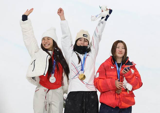 Snowboarder Choi Ga-on, center, celebrates while holding the gold medal during the women’s halfpipe medal ceremony at the 2026 Milan-Cortina Winter Olympics at Livigno Snow Park in Italy on Feb. 12. From left are silver medalist Chloe Kim of the United States, Choi and bronze medalist Mitsuki Ono of Japan. [NEWS1]