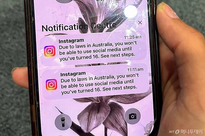 지난 9일 호주 시드니에서 한 10대 청소년이 소셜미디어 플랫폼 인스타그램 계정이 연령확인을 위해 잠긴 계정의 메시지가 표시된 휴대전화를 들고 있다. /시드니(호주) AFP=뉴스1