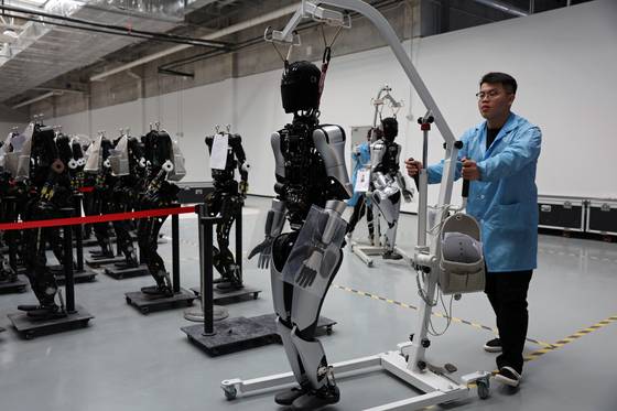 중국 상하이 애지봇 공장에서 직원들이 휴머노이드 로봇을 옮기고 있다. [로이터=연합뉴스]