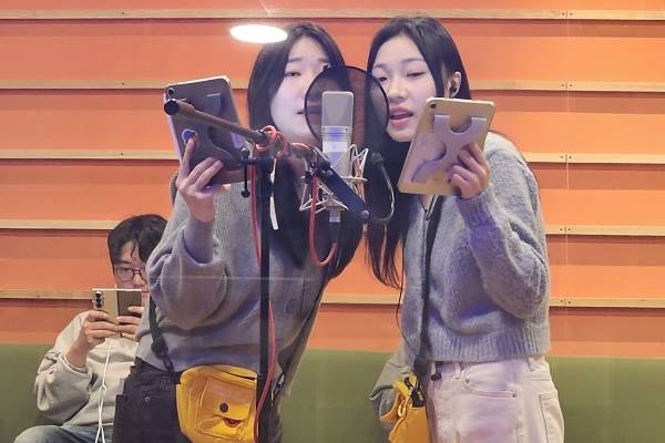 ▲지난달 27일 서울 마포구 상암동 대원방송에서 '디지몬 비트브레이킹' 더빙 중인 성우들. 같은 장면에서 나오는 목소리를 연기하는 두 명의 성우가 하나의 마이크 앞에서 연기하고 있다. 노란 가방에는 모니터링을 위한 이어폰이 연결돼 있다. 사진=미디어오늘