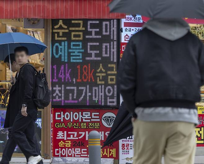 People pass by an electronic sign advertising gold purchases lit at a shop in Jongno District, central Seoul, on April 14, 2025. [NEWS1]