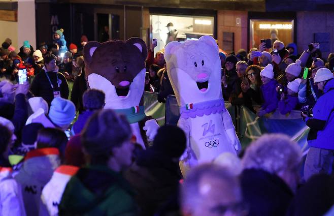 6일(현지시간) 이탈리아 밀라노에서 열리는 밀라노·코르티나 2026 동계올림픽 개막식을 앞두고, 자원봉사자들이 마스코트 ‘티나(Tina)’와 ‘밀로(Milo)’의 사진을 찍고 있다. [로이터]