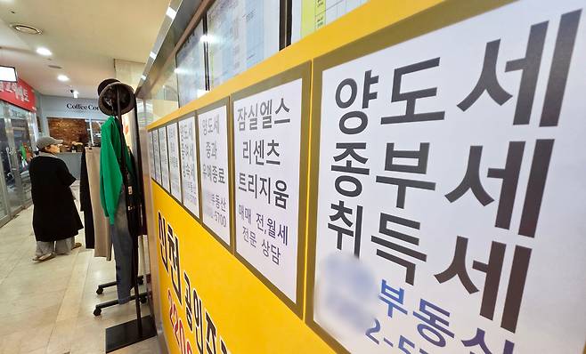 12일 서울 시내 한 공인중개사 사무실 외벽에 부동산 관련 세금과 아파트 매매 물건 등의 안내문이 게시되어 있다. /연합뉴스