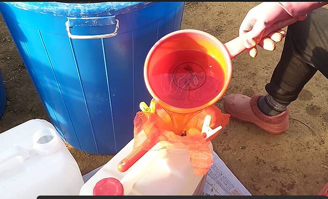 완성된 천연 유황 농약을 통에 따르고 있다.