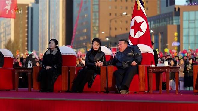 김정은 북한 국무위원장이 부인 리설주, 딸 주애와 함께 지난 16일 평양 화성지구 4단계 1만 세대 살림집 준공식 경축공연을 관람하던 중 주애가 김 위원장이 펼친 손을 두 손으로 어루만지고 있다. 조선중앙TV 연합뉴스