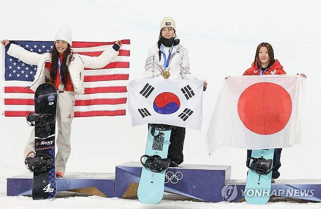 스노보드 선수 최가온(가운데)이 지난 12일(현지시간) 2026 밀라노·코르티나 동계올림픽 스노보드 여자 하프파이프 종목에서 우승한 뒤 시상대에서 금메달을 목에 걸고 태극기와 함께 기념촬영을 하고 있다. 연합뉴스