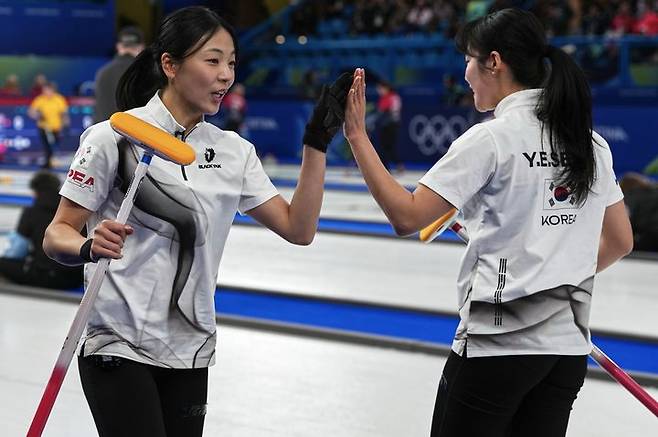 [코르티나담페초=AP/뉴시스] 한국 여자 컬링 대표팀(경기도청) 김민지와 설예은이 15일(현지 시간) 이탈리아 코르티나담페초의 코르티나 컬링 올림픽 스타디움에서 열린 2026 밀라노·코르티나 동계올림픽 컬링 라운드로빈 5차전 일본과 경기 중 하이파이브를 하고 있다. 한국이 7-5로 승리해 3승2패를 기록했다.  2026.02.16.