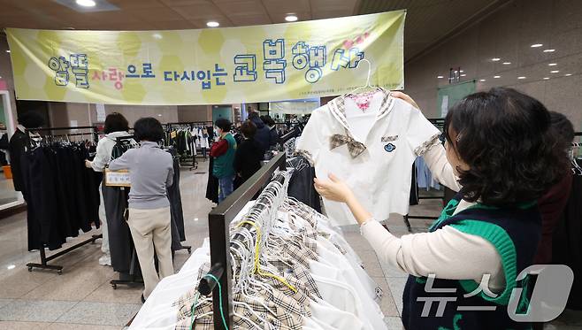 이재명 대통령이 최근 60만 원에 육박하는 교복 가격 적정성 검토를 지시한 가운데 지난 5일 경기 과천시 과천시민회관 녹색가게 앞 로비에서 열린 '제29회 알뜰사랑으로 물려입는 교복 행사'에서 학부모들이 기부된 과천시 관내 중·고등학교 교복을 구매하고 있다. 2026.2.5 ⓒ 뉴스1 김영운 기자