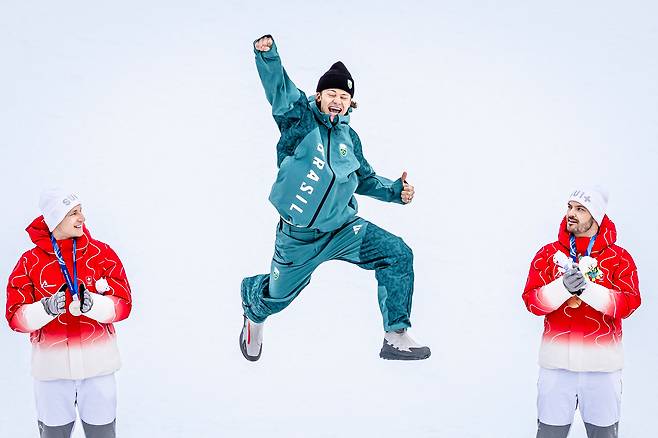 브라질의 루카스 피네이루 브라텐(가운데)이 15일 알파인스키 남자 대회전 시상식에서 2위 마르코 오데르마트(왼쪽)와 3위 로익 밀라드(이상 스위스)가 지켜보는 가운데 오른팔을 쭉 뻗은 채 높이 뛰어오르며 자축하고 있다. 브라텐은 남미 출신의 첫 동계 올림픽 메달리스트다./ EPA 연합뉴스
