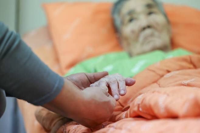 하선규씨의 노모가 지난달 19일 경기 안산의 한 요양 병원에서 자기 손을 주무르는 아들 하씨를 말없이 바라보고 있다. 하씨는 2억원을 대출받아 치매 등을 앓고 있는 노모의 간병비를 대고 있다./박성원 기자