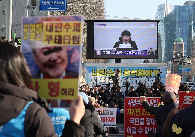 촛불행동 관계자들이 19일 서울 서초구 서울중앙지법 인근에서 12·3 비상계엄과 관련해 내란 우두머리 혐의로 기소된 윤석열 전 대통령에 대한 1심 선고 생중계를 시청하고 있다. /연합뉴스