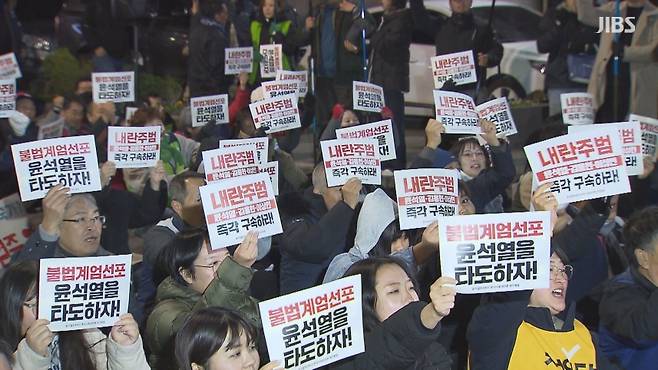 비상계엄에 반대하는 시민들이 집회에서 구호가 적힌 손팻말을 들고 있다.