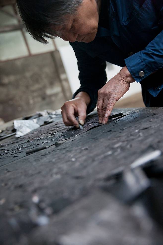 ‘신문 지우기’ 작업 중인 최병소(1943~2025). 50년간 볼펜과 연필을 그으며 신문을 지워나간 그의 오른쪽 검지에는 점처럼 검은 잉크 자국이 박혔다. [사진 페로탕]