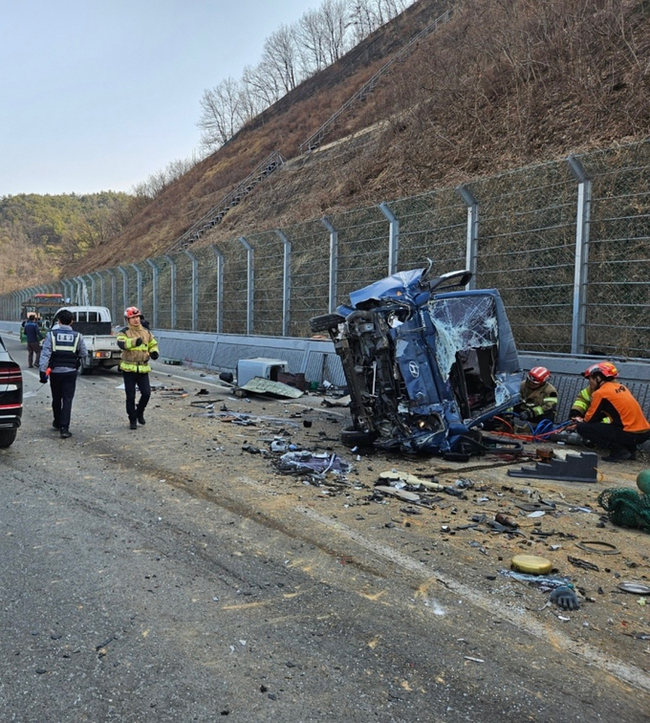 ▲ 경북 의성군 비안면 쌍계리 도로에서 21일 의성소방서 구조대원과 경찰관들이 도로 우측 방음벽 옆에 전도된 트럭 주변에서 유압 장비를 사용해 구조 작업을 벌이고 있다. 의성소방서 제공
