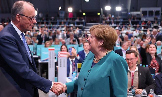 20일(현지시간) 독일 슈투트가르트에서 열린 CDU 전당대회 행사 도중 프리드리히 메르츠(왼쪽) 총리가 과거 오랜 기간 라이벌이었던 앙겔라 메르켈 전 총리와 악수를 나누고 있다. 로이터연합뉴스