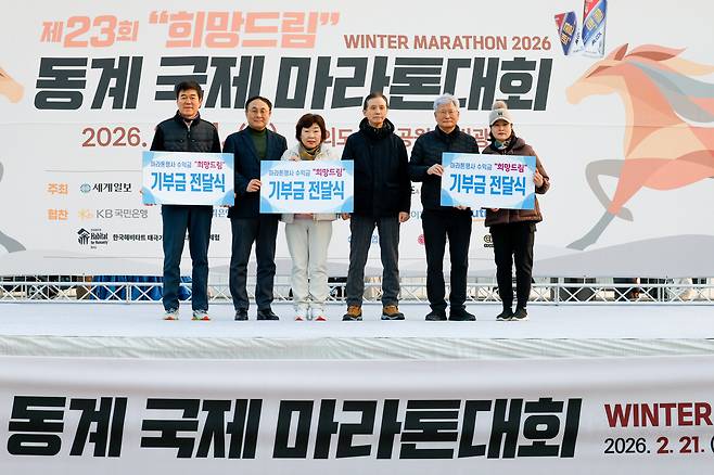 신규택 세계일보 대외협력국 국장(왼쪽 두번째), 정지명 한국마라톤협회 총재(왼쪽 네번째) 김주현 한국마라톤협회 명예회장(오른쪽 두번째)이 21일 서울 영등포구 여의도 한강공원 물빛광장에서 열린 희망드림 ‘제23회 동계 국제 마라톤대회’에서 기부금을 전달하고 있다.