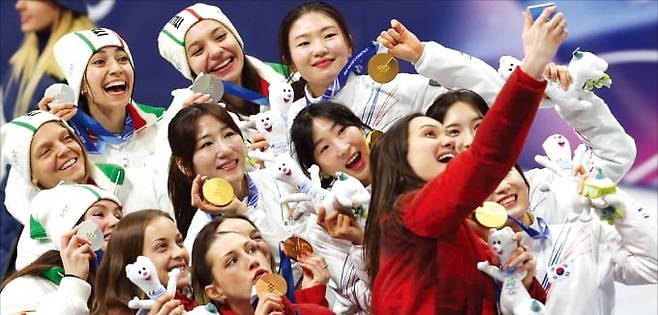 지난 19일 이탈리아 밀라노 아이스스케이팅 아레나에서 열린 2026 밀라노-코르티나담페초 동계올림픽 쇼트트랙 여자 3000m 계주 시상식에서 금메달을 목에 건 한국 여자 대표팀 선수들이 이탈리아(은메달), 캐나다(동메달) 선수들과 ‘빅토리 셀피’를 찍고 있다.  연합뉴스