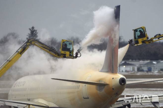 [로물루스=AP/뉴시스]  미국 미시간주 로물루스의 디트로이트 메트로폴리탄 웨인 공항에서 공항 관리공단 측이 델타항공 항공기의 얼음을 제거하고 있다. 미 중·동부에 내린 폭설로 이 당시 최소 5명이 숨지고 정전과 교통마비 등 피해가 잇따랐다. 2026.02.22.