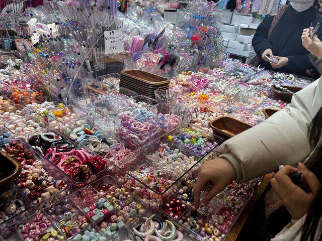 방문객이 다양한 볼펜 장식 액세서리 중 마음에 드는 것을 고르는 모습.