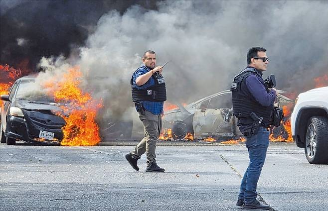 < 폭력사태 이어지는 멕시코 > 멕시코 경찰이 22일(현지시간) 할리스코주 사포판 지역에서 도로를 통제하고 있다. 멕시코 국방부가 ‘먀약왕’ 네메시오 오세게라를 사살하자 마약 조직원들이 차량에 불을 질러 도로 차단을 시도하는 등 폭력 사태가 이어졌다.  로이터연합뉴스