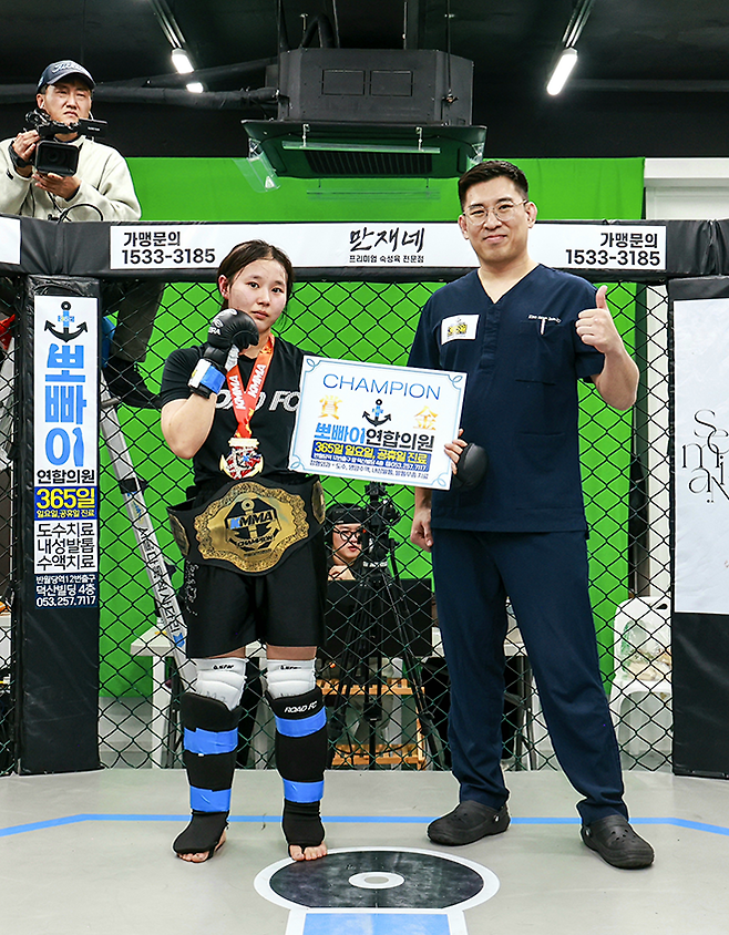 정민지가 2025년 12월 초대 KMMA 여성부 플라이급 챔피언 등극 후 김성배 뽀빠이연합의원 원장 겸 KMMA 파이터 에이전시 대표이사와 기념 촬영을 하고 있다. 사진=스탠다드앤드프로그레스 스포츠에이전시 제공