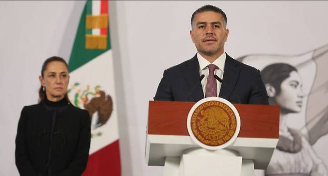 [멕시코시티=AP/뉴시스] 23일 멕시코시티 대통령궁에서 열린 정례 기자회견에서 오마르 가르시아 하르푸치 안보·시민보호부 장관이 전날 마약 카르텔 조직 두목 사살 등에 대해 발표학 있다. 클라우디아 셰인바움 대통령이 뒤에서 이를 지켜보고 있다.2026.02.24. *재판매 및 DB 금지