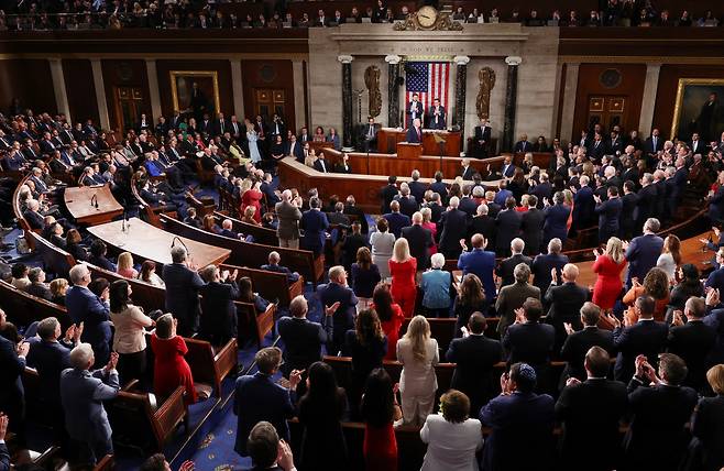 트럼프 대통령의 국정연설에서 공화당 의원들이 박수를 치며 일어나 있는 가운데, 왼편에 앉은 민주당 의원들은 모두 자리에 앉아 있는 모습 (사진: 로이터)